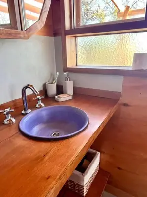 a bathroom counter with a blue sink and a window at Mandala Tiny House, Traslasierra. in Yacanto