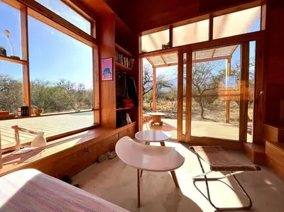 a room with a bed and two tables and windows at Mandala Tiny House, Traslasierra. in Yacanto