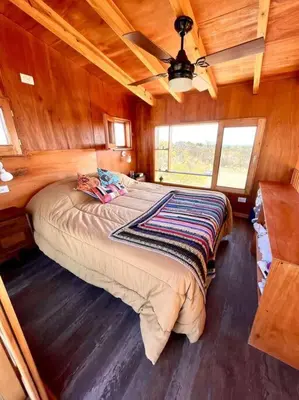 a bedroom with a large bed in a wooden room at Mandala Tiny House, Traslasierra. in Yacanto