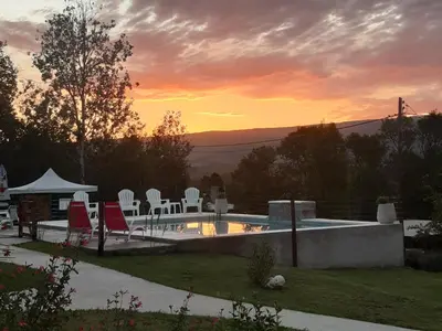 a pool with chairs and a sunset in the background at Gemas Apart in Villa Yacanto
