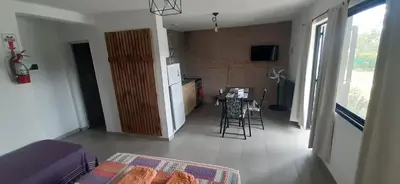 a living room with a kitchen and a table with chairs at Gemas Apart in Villa Yacanto