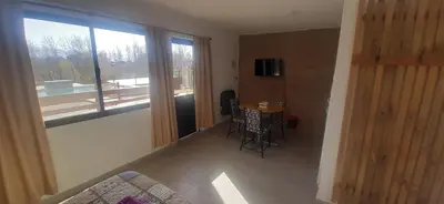 a living room with a table and a large window at Gemas Apart in Villa Yacanto