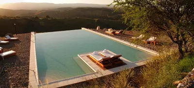 a swimming pool with a table and chairs in it at Posada Loma del Tigre in Los Reartes