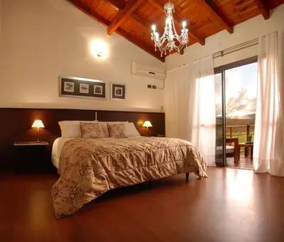 a bedroom with a large bed and a chandelier at Posada Loma del Tigre in Los Reartes