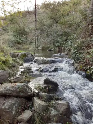 a stream of water with rocks on the side of a hill at Posada Loma del Tigre in Los Reartes