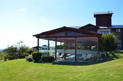 a house with a conservatory with chairs and a pool at Posada Loma del Tigre in Los Reartes