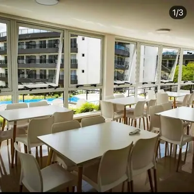 a restaurant with white tables and chairs and windows at Departamento con vistas al lago en Veneto Village in Villa Parque Siquiman