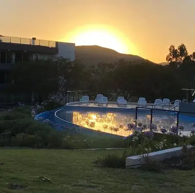 a pool with chairs and the sunset in the background at Departamento con vistas al lago en Veneto Village in Villa Parque Siquiman