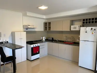 a kitchen with white appliances and a table in it at Departamento con vistas al lago en Veneto Village in Villa Parque Siquiman