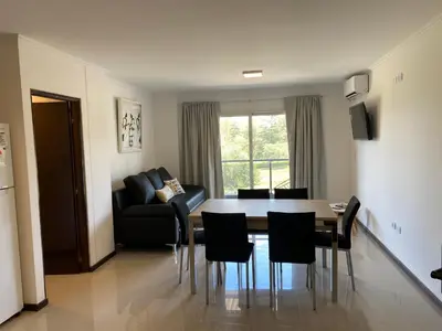 a living room with a table and chairs and a couch at Departamento con vistas al lago en Veneto Village in Villa Parque Siquiman