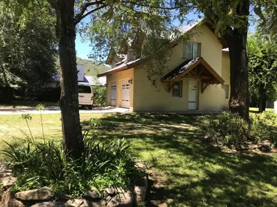 a house with trees in front of a yard at LA CASONA in Villa General Belgrano