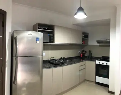 a kitchen with a stainless steel refrigerator and white cabinets at Edificio Veneto IV - Departamento de un dormitorio en pleno centro in Villa Carlos Paz