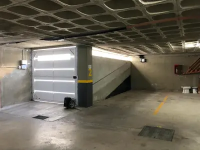 an empty parking garage with a white garage door at Edificio Veneto IV - Departamento de un dormitorio en pleno centro in Villa Carlos Paz