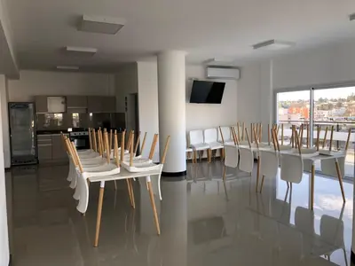 a dining room with white tables and white chairs at Edificio Veneto IV - Departamento de un dormitorio en pleno centro in Villa Carlos Paz