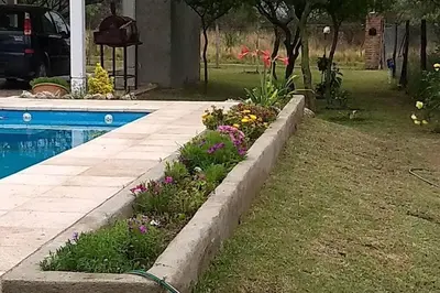 a garden with flowers next to a swimming pool at Confortable casa traslasierra. Vista al Champaqui in Quebrada de los Pozos