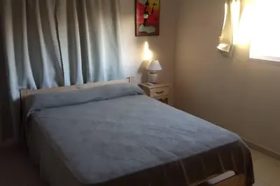 a bedroom with a bed with a blue blanket and a window at Confortable casa traslasierra. Vista al Champaqui in Quebrada de los Pozos