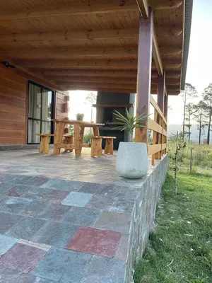 a porch of a house with a table and a bench at Complejo Anthea in Villa Yacanto