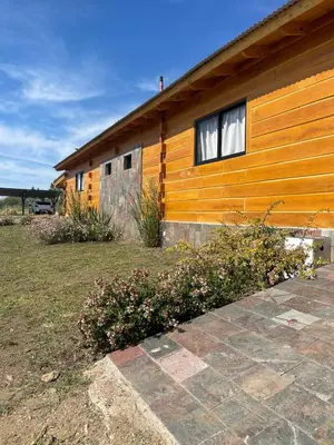 a house with a yellow wall and some flowers at Complejo Anthea in Villa Yacanto