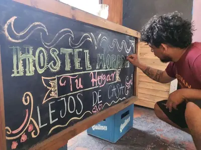 a man is writing on a chalkboard at Morada Hostel & Bar in Cordoba
