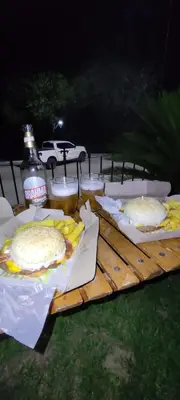 a table with sandwiches and french fries and a bottle of soda at Terraza Perito Moreno in Villa Carlos Paz