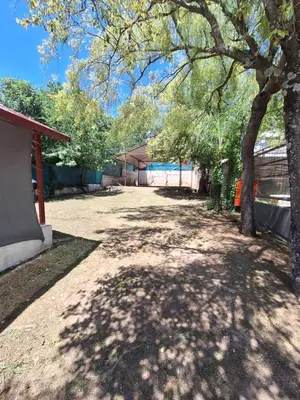 a shady yard with a tree and a building at Terraza Perito Moreno in Villa Carlos Paz