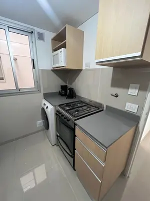 a small kitchen with a stove and a microwave at Dpto Nva Cba, pileta seguridad, cochera in Cordoba