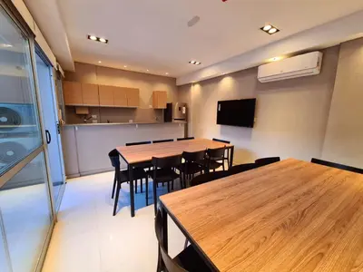 a dining room with tables and chairs and a kitchen at Dpto Nva Cba, pileta seguridad, cochera in Cordoba
