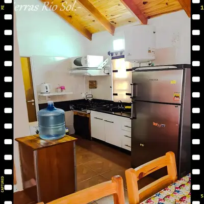 a kitchen with a stainless steel refrigerator and a stove at Cabaña en las Sierras, Sierras Rio Sol!!! Espectacular Cabaña Frente al Rio y las Sierras in Santa María