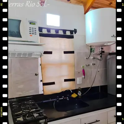 a kitchen with a sink and a stove and a microwave at Cabaña en las Sierras, Sierras Rio Sol!!! Espectacular Cabaña Frente al Rio y las Sierras in Santa María