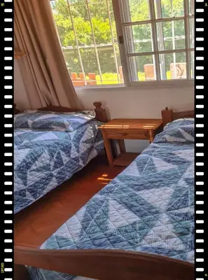 a bedroom with two beds and a table and windows at Cabaña en las Sierras, Sierras Rio Sol!!! Espectacular Cabaña Frente al Rio y las Sierras in Santa María