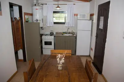 a kitchen with a table and a white refrigerator at Cabañas Los 2 Algarrobos in Santa Rosa de Calamuchita