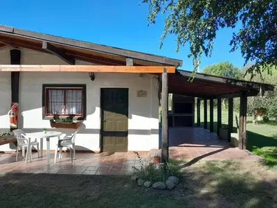 a patio with a table and chairs in front of a house at Cabañas Los 2 Algarrobos in Santa Rosa de Calamuchita