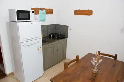 a kitchen with a table and a refrigerator and a microwave at Cabañas Los 2 Algarrobos in Santa Rosa de Calamuchita