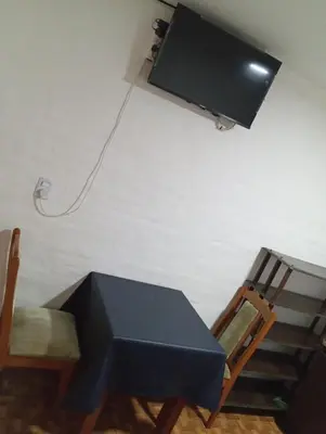 a black table and a chair and a television on a wall at Sierras Altas Alojamientos in Villa Carlos Paz