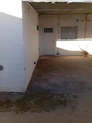 an empty garage with a white wall and a door at Sierras Altas Alojamientos in Villa Carlos Paz