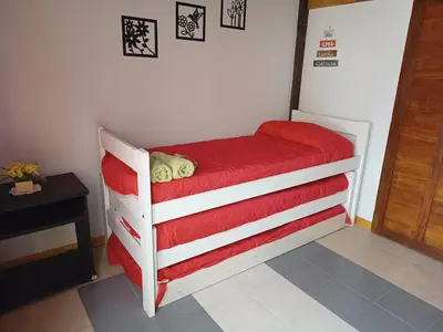 a small bed in a room with a red blanket at Casita del Río in Santa Rosa de Calamuchita