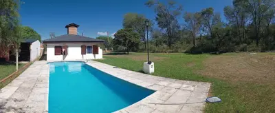 a swimming pool in a yard next to a house at Casita del Río in Santa Rosa de Calamuchita