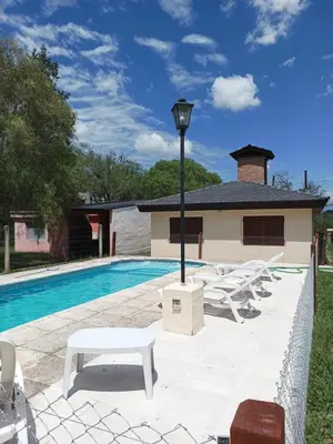 a pool with white lounge chairs and a light pole at Casita del Río in Santa Rosa de Calamuchita