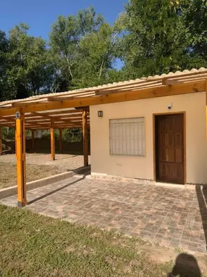 a building with a garage with a door and a patio at Casita del Río in Santa Rosa de Calamuchita