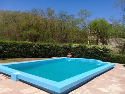 a person is sitting in a blue swimming pool at Cabaña La Raquela in La Paz