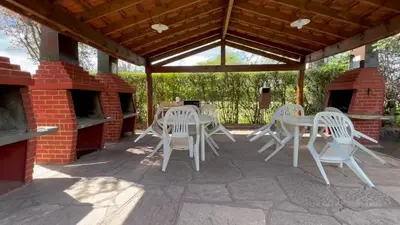 a patio with white tables and chairs under a pavilion at Cabañas Agua que Brilla in Mina Clavero
