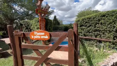 a wooden gate with a sign on top of it at Cabañas Agua que Brilla in Mina Clavero