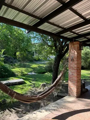 a hammock hanging under a porch with a tree at Casita de Cuesta in Villa Icho Cruz