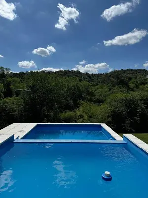 a blue swimming pool with a view of the forest at Casita de Cuesta in Villa Icho Cruz