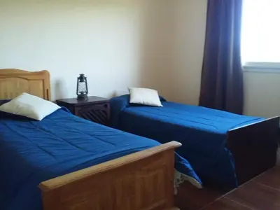 a bedroom with two beds with blue sheets and a window at Casa en Villa Los Aromos in La Bolsa