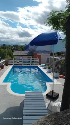 a large blue swimming pool with an umbrella at CABAÑAS BALCON DE PEHUMAYEN in Villa Carlos Paz