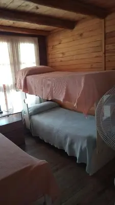 a bedroom with two beds in a log cabin at CABAÑAS BALCON DE PEHUMAYEN in Villa Carlos Paz