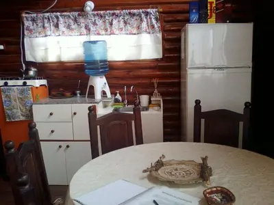 a kitchen with a table and a refrigerator at CABAÑAS BALCON DE PEHUMAYEN in Villa Carlos Paz