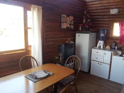a kitchen with a table and a refrigerator at CABAÑAS BALCON DE PEHUMAYEN in Villa Carlos Paz