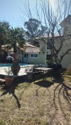 a house with a statue in front of a yard at Cabaña Paulina in Santa Rosa de Calamuchita